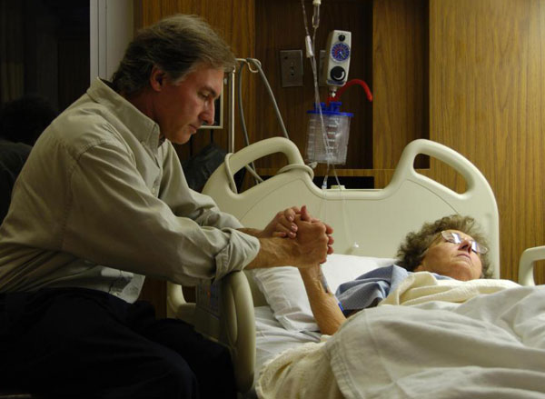 man-sitting-with-older-woman-in-hospital-bed-holding-her-hand.jpg